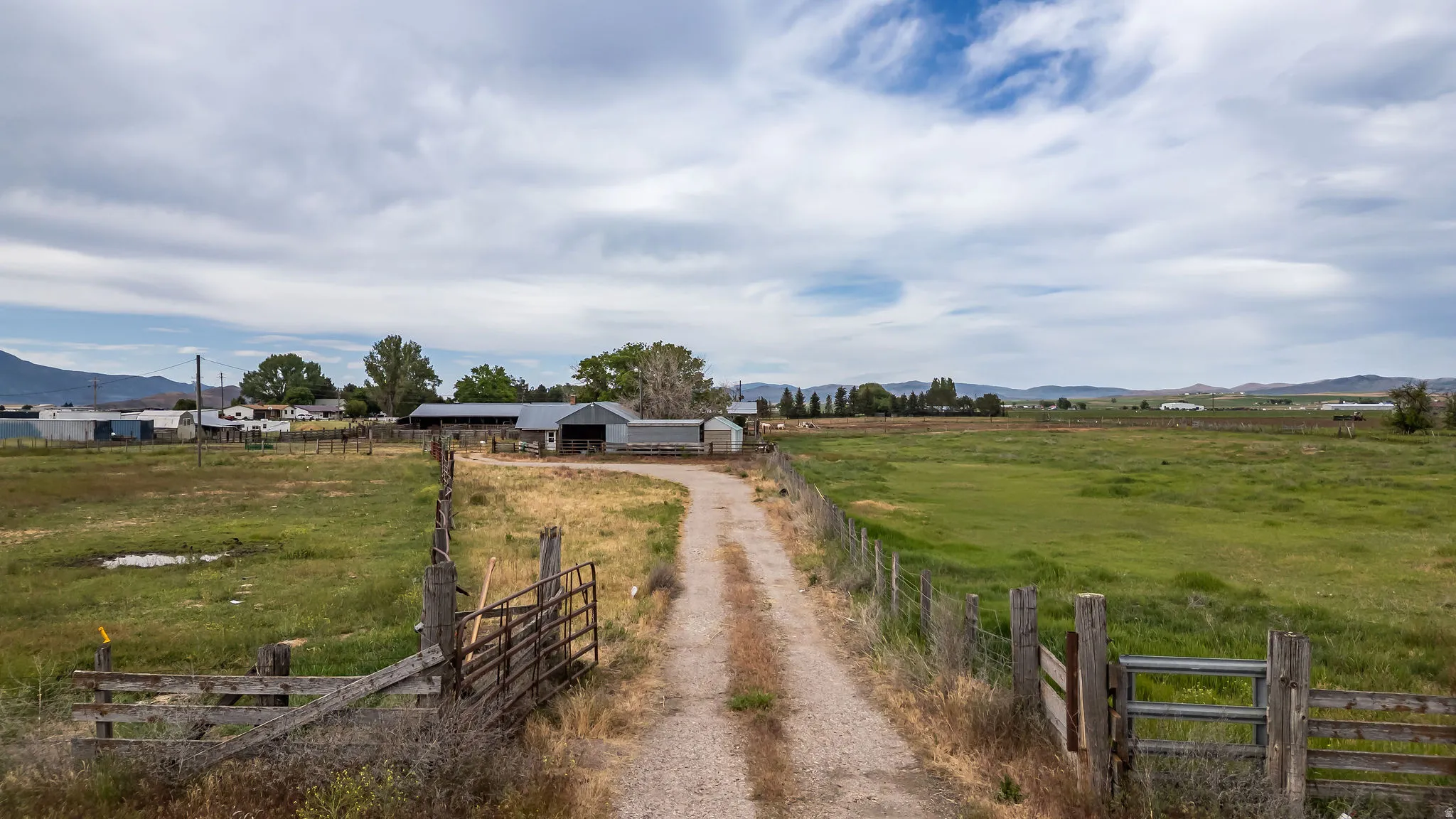 Gravel driveway extending through open fields