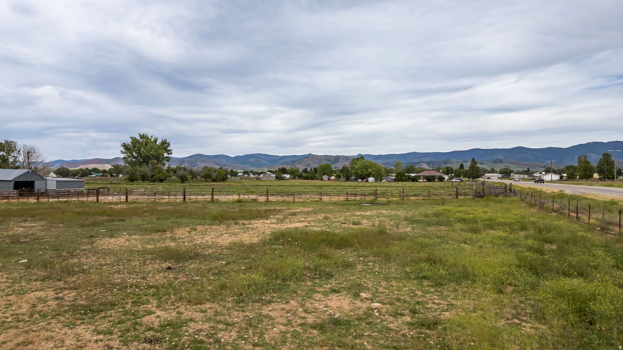 Expansive open field with partial fencing and distant mountain ranges
