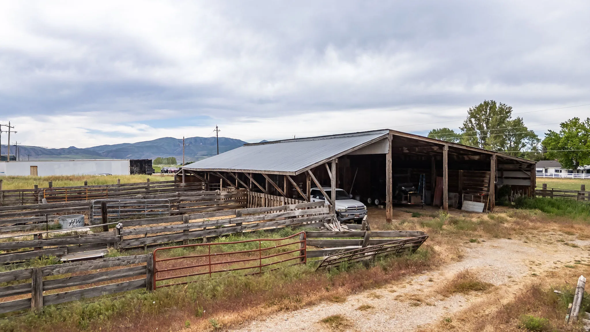 Open-sided barn structure with a corrugated metal roof, featuring multiple bays for storage or shelter