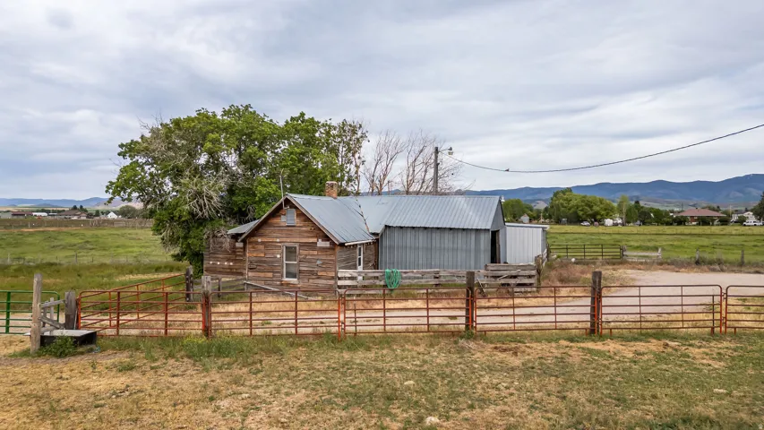 Rustic wood-sided dwelling with a metal roof, accompanied by a corrugated metal outbuilding