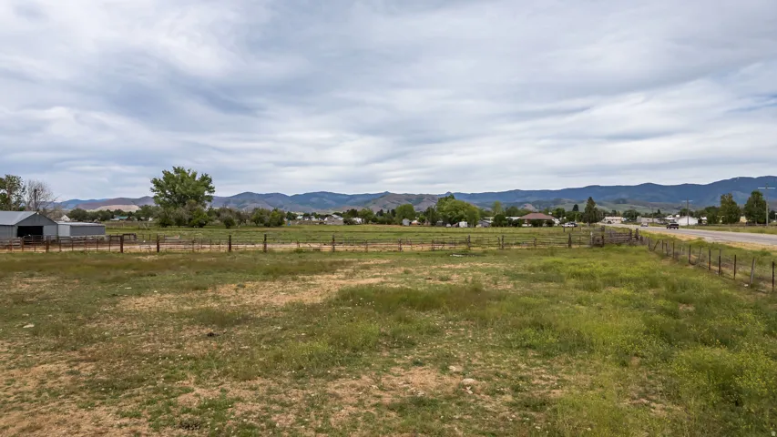 Expansive open field with partial fencing and distant mountain ranges