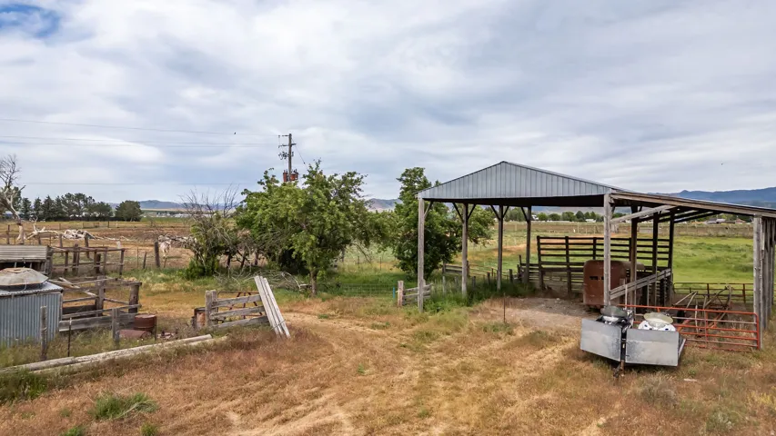 Expansive open-air barn with a metal roof and wood posts, featuring an interior wood fence