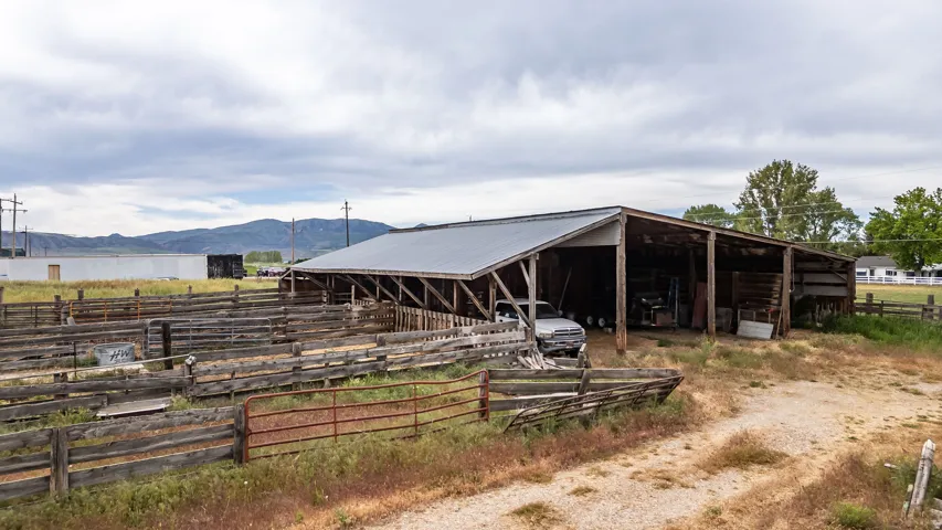 Open-sided barn structure with a corrugated metal roof, featuring multiple bays for storage or shelter