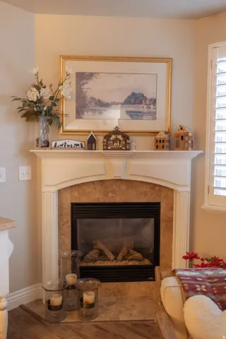 Corner fireplace featuring a stone surround, traditional white mantel, and built-in gas insert