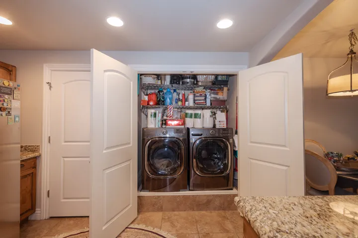 Integrated laundry area featuring tile flooring and double panel doors