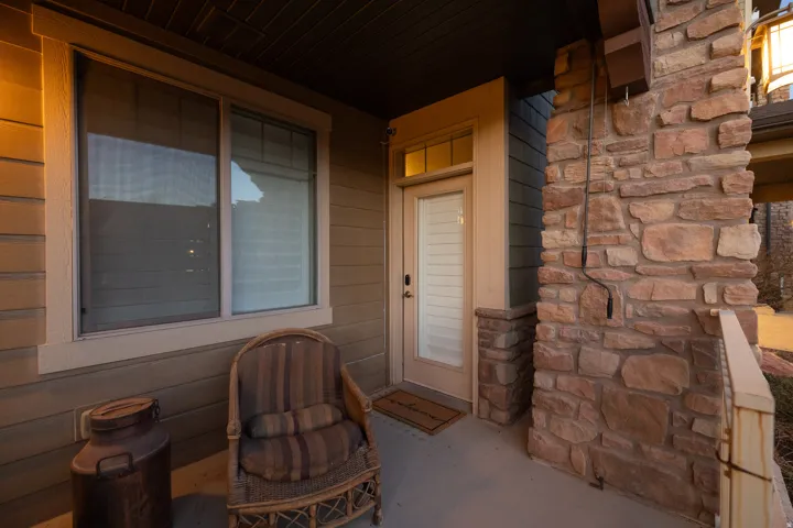 Covered entryway featuring stone-clad columns and horizontal siding