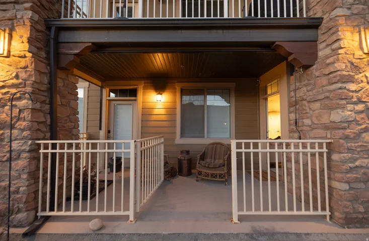 Covered porch with stone column accents, horizontal siding, and a white metal railing