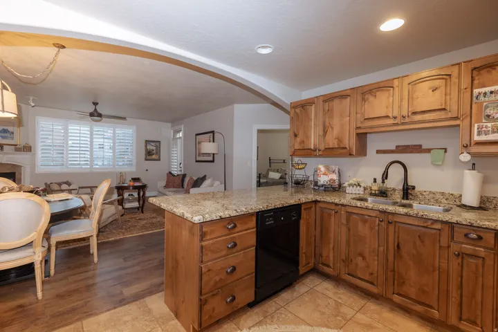 Kitchen featuring wood cabinetry, granite countertops, black appliances, and tile flooring