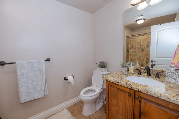 Bathroom featuring a vanity with granite countertop, undermount sink, and wood-finish cabinetry