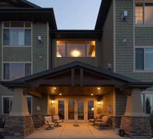 Entryway featuring double glass doors, stone column bases, and a covered porch with recessed lighting