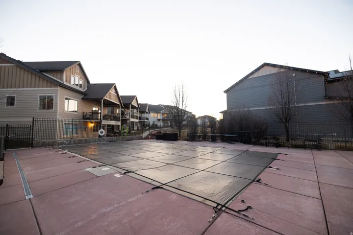 Expansive covered swimming pool area featuring a concrete deck and surrounding metal fencing