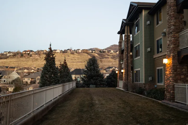 Multi-story building featuring stone veneer columns, horizontal siding, and multiple balconies with white railings