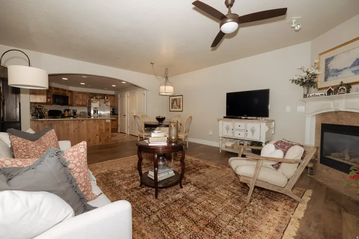 Living area featuring wood-finish flooring, a ceiling fan, and a fireplace with a mantel
