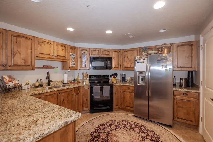 Kitchen featuring wood cabinetry, light-toned granite countertops, and stainless steel appliances