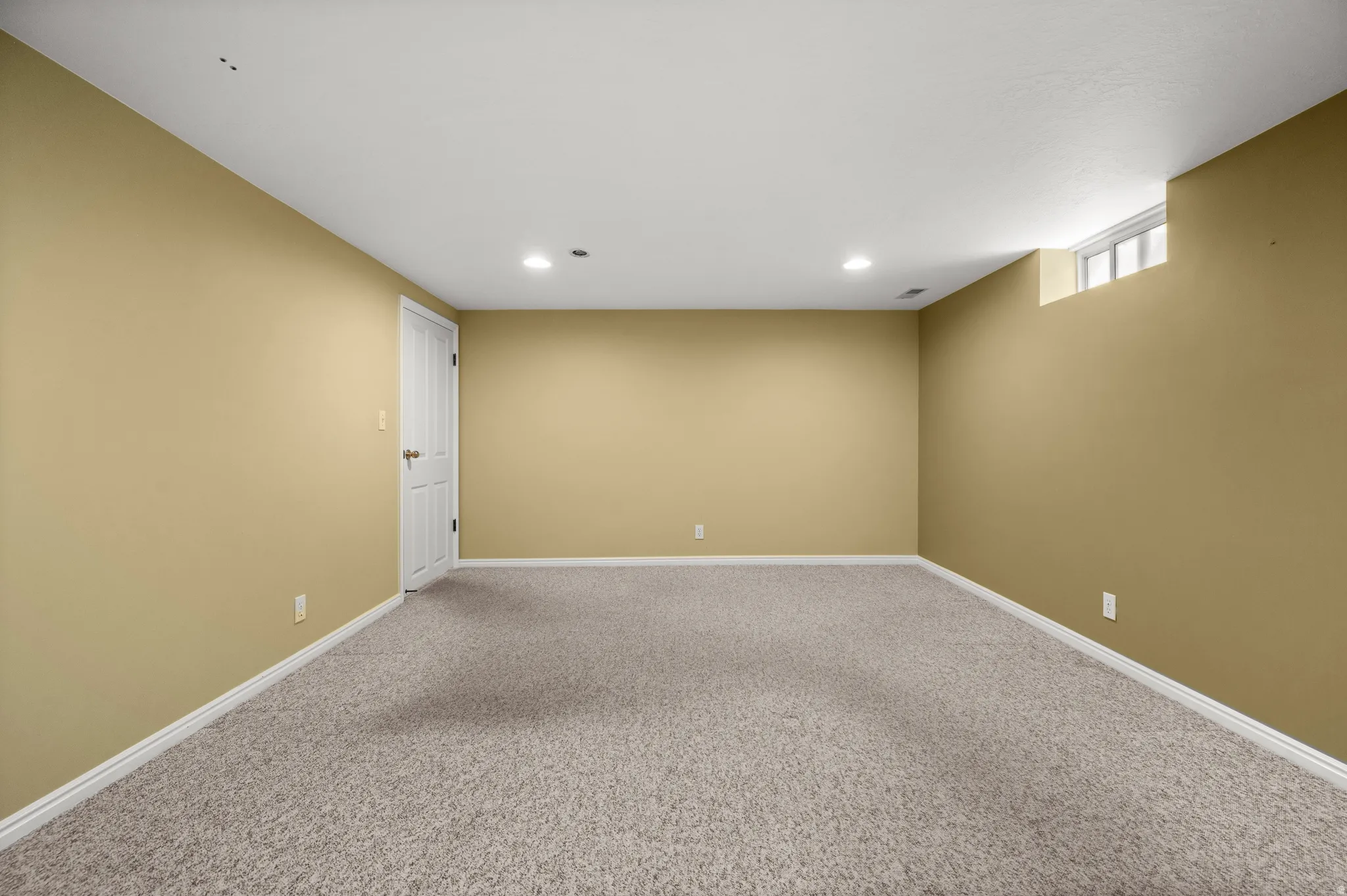 Spacious room with light tan walls and light gray carpet