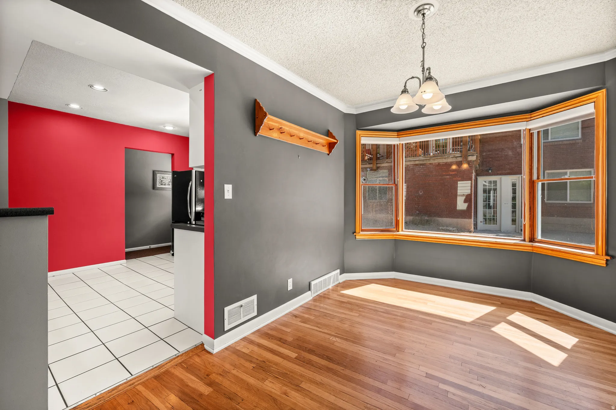 Hardwood flooring throughout a room featuring a bay window with natural wood trim