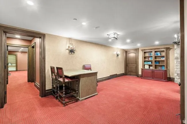 Spacious interior room featuring textured wall coverings, recessed lighting, and a built-in wood cabinet with shelving