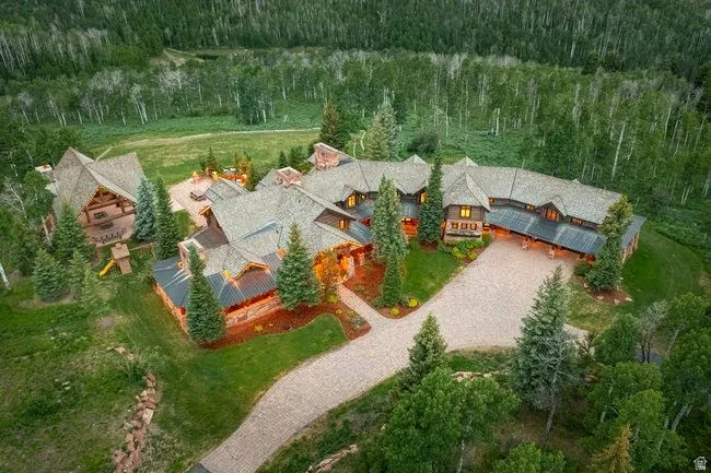 Expansive rustic-style residence featuring a multi-gabled roofline, stone and wood-clad exterior, and a gravel driveway