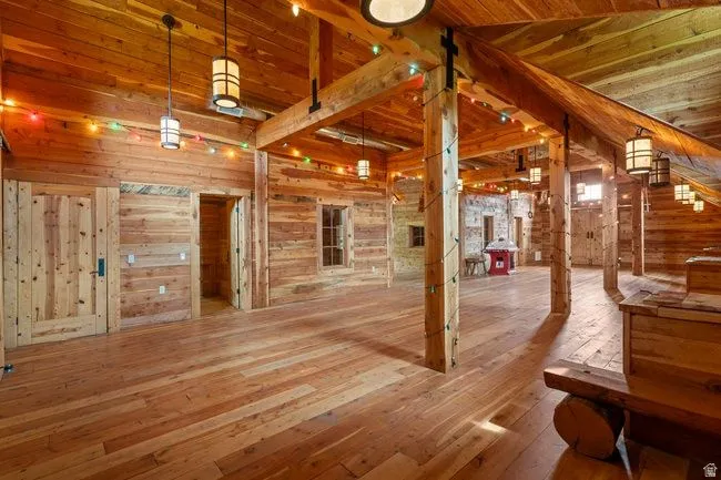 Spacious interior featuring extensive wood-finish flooring, exposed wooden beams, and plank wood walls