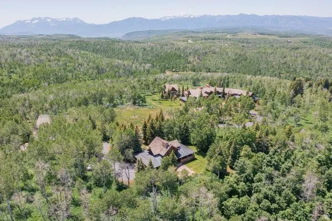 Expansive wooded landscape featuring multiple properties and distant mountains