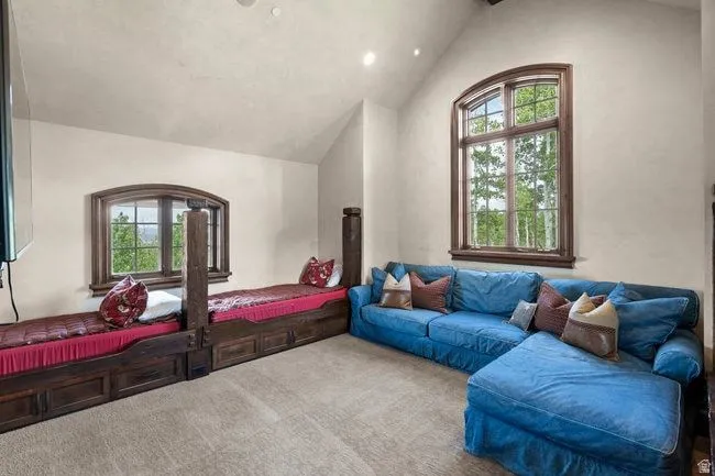Vaulted ceiling room featuring a large arched wood-frame window, two built-in wood-finish beds with storage drawers, and recessed lighting