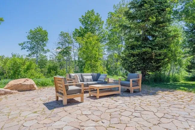 Expansive stone patio featuring irregular flagstone pavers and surrounding mature trees
