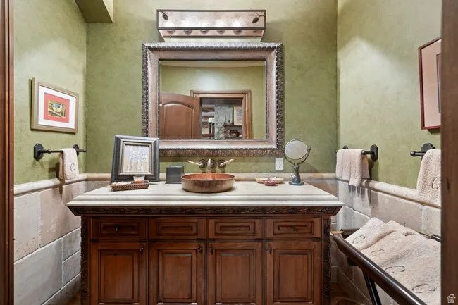 Vanity area featuring a stone-look countertop, integrated copper vessel sink, and ornate framed mirror