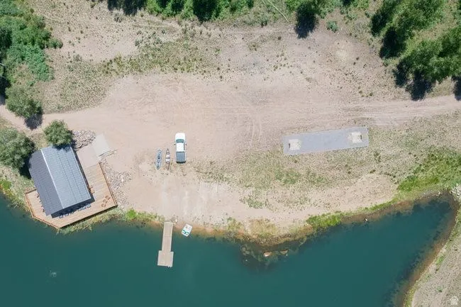 Waterfront property featuring a private dock, boat ramp, and a structure with a dark roof and surrounding wood decking