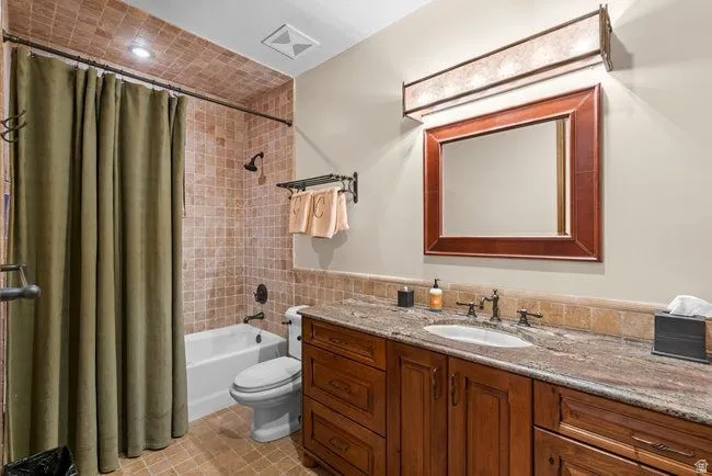 Bathroom featuring a wood-finish vanity with an integrated sink and a stone countertop