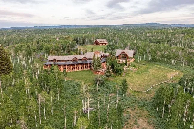 Expansive multi-structure property featuring log cabin construction, gabled roofs, and an established lawn