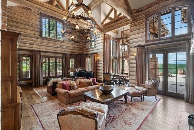Expansive living area featuring exposed log walls, a vaulted ceiling with exposed wood beams, and wood-finish flooring
