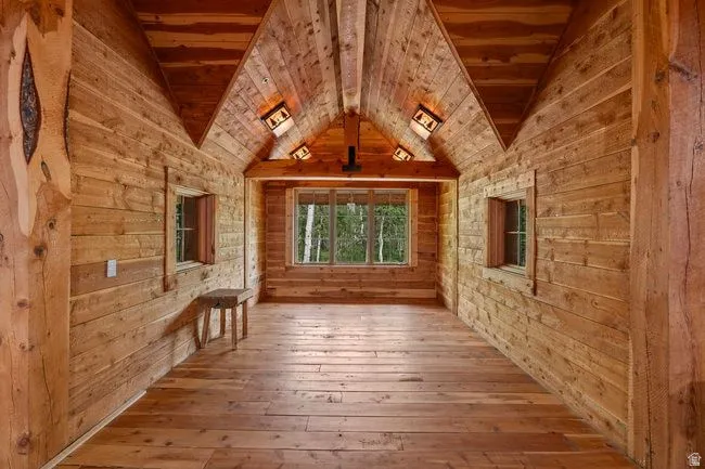 Expansive room featuring natural wood plank walls, exposed wood beam ceiling, and wood-finish flooring