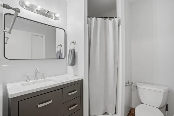 Bathroom featuring a vanity with a white countertop and integrated sink, dark wood-finish cabinetry, and brushed nickel hardware