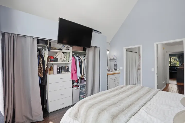 Bedroom featuring high vaulted ceilings, hardwood-finish flooring, and a closet with custom built-in organization