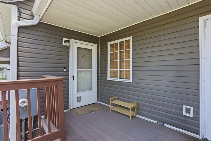 Covered porch entry featuring horizontal siding, white trim, and a white screen door