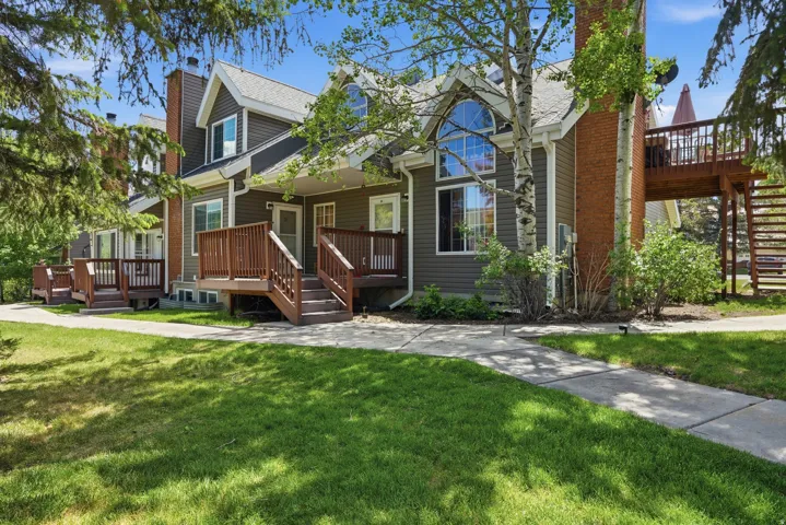 Multi-level dwelling with dark siding, featuring a prominent arched window and a raised wooden deck