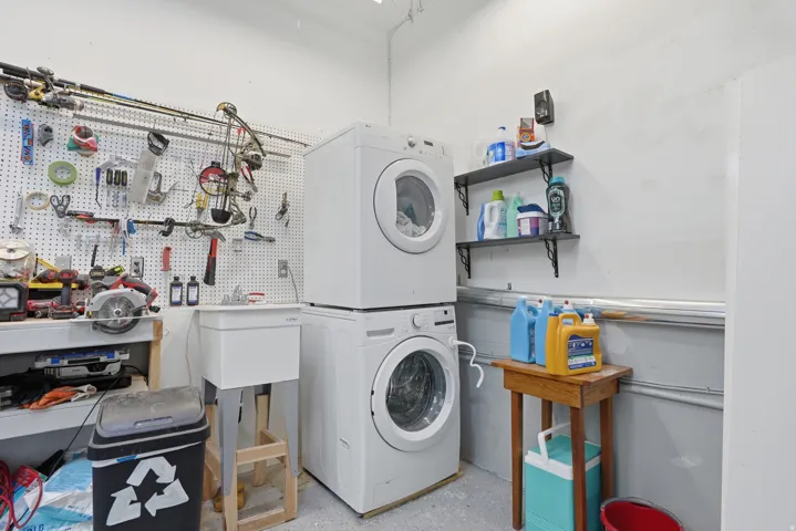 Dedicated utility space featuring a stacked washer and dryer, a utility sink, and wall-mounted shelving