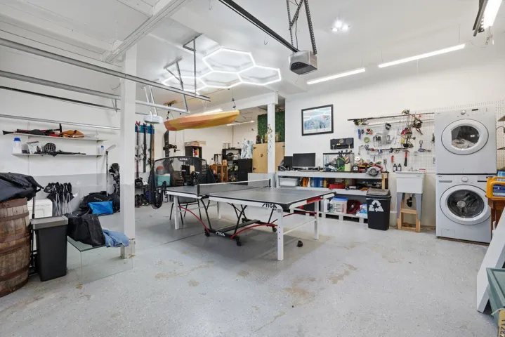 Spacious multi-purpose garage featuring a washer and dryer unit, utility sink, and built-in shelving