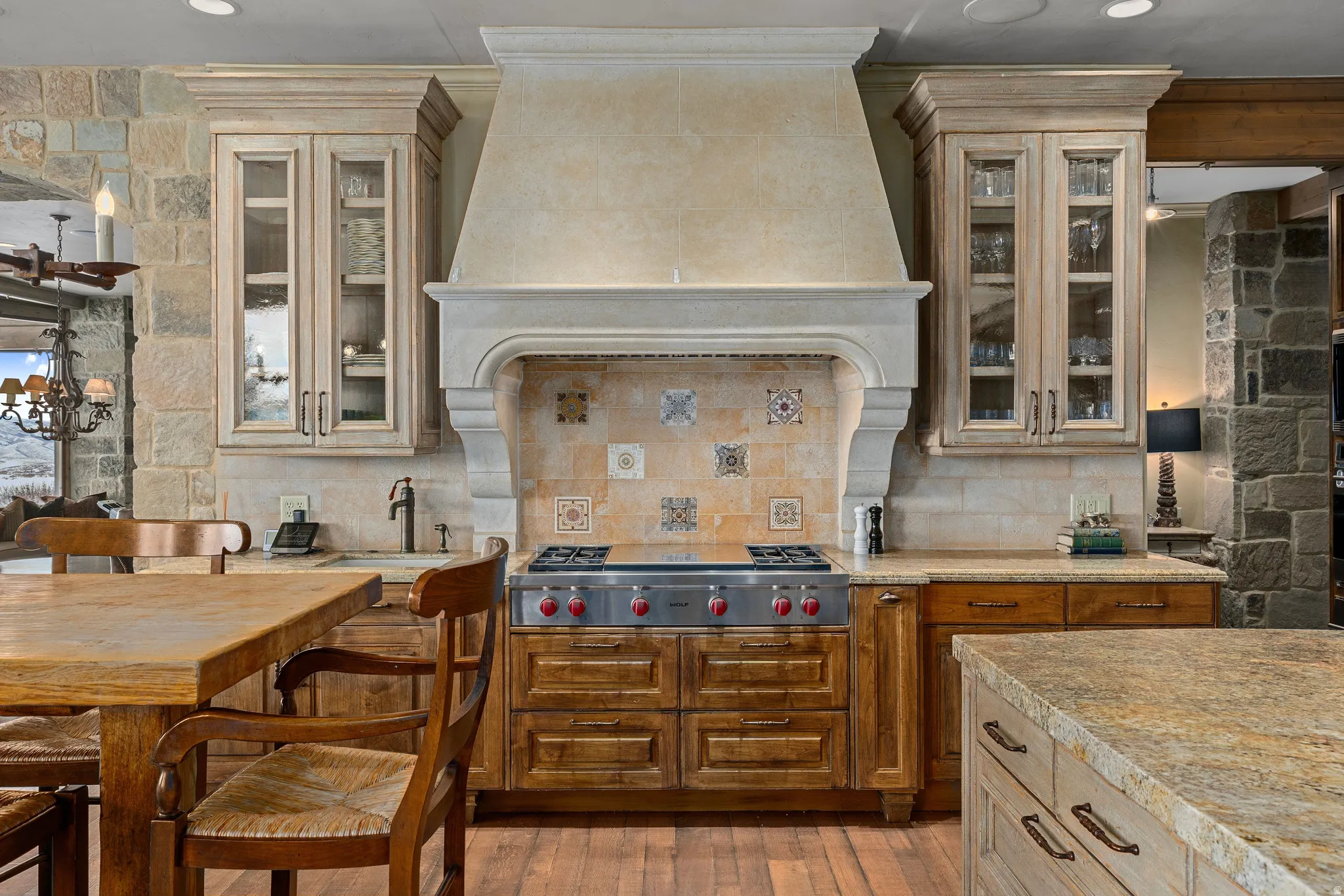 Gourmet kitchen featuring a substantial range hood, a professional-grade gas range, and a tiled backsplash with decorative accents