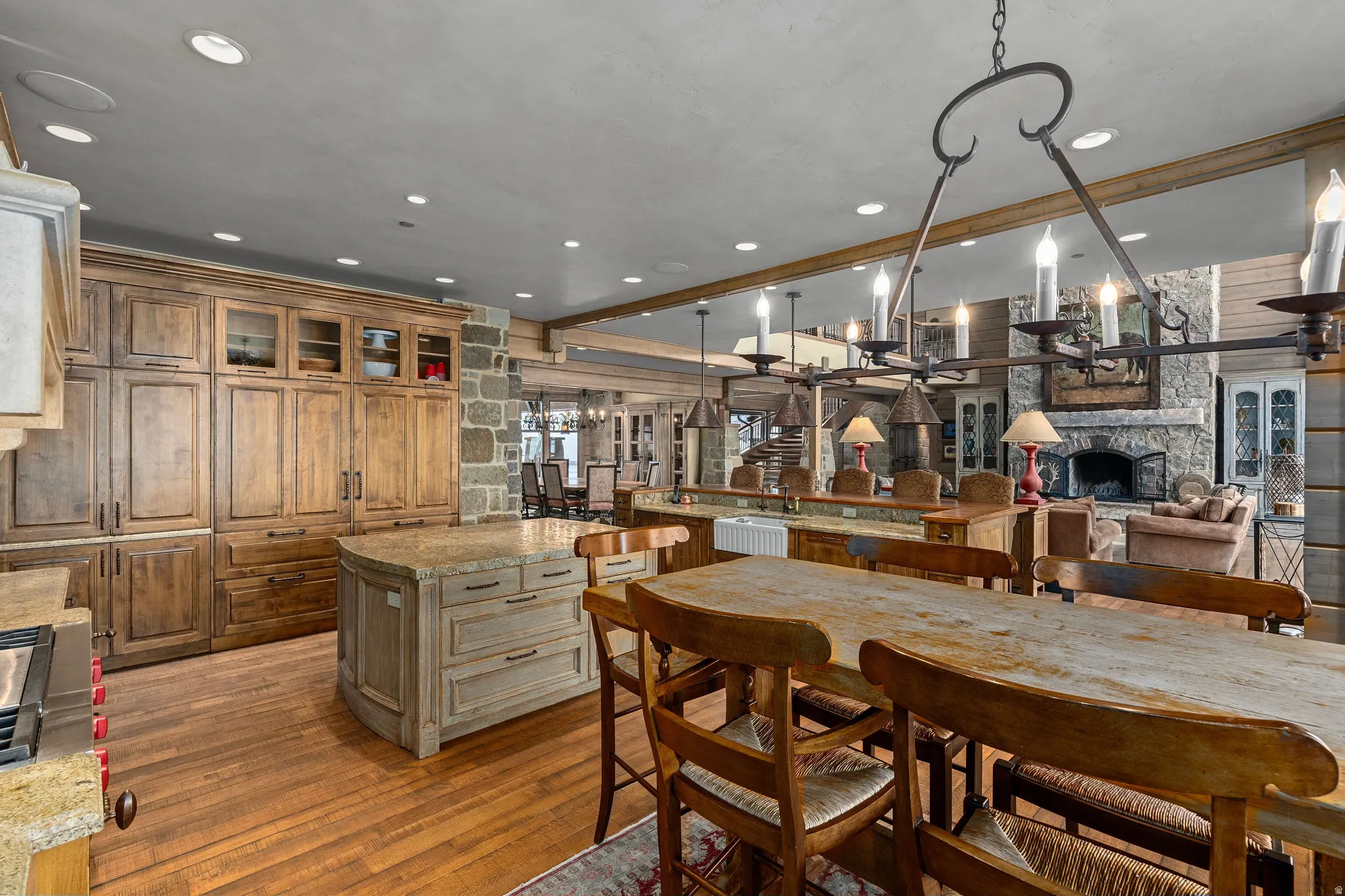 Spacious kitchen with wood-finish flooring, custom cabinetry featuring glass-front uppers, and a stone-clad support column