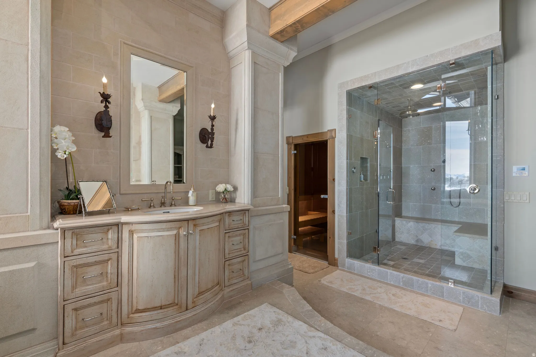 Spacious bath featuring a light wood vanity with an undermount sink, a large framed mirror, and two wall-mounted sconces