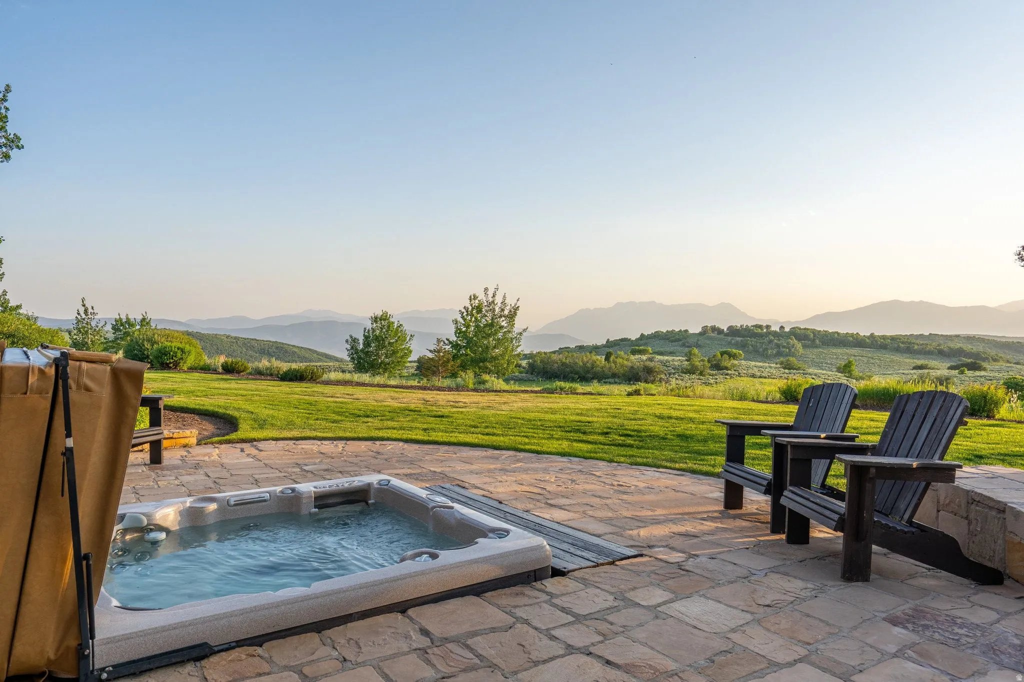 Stone patio featuring an in-ground hot tub and expansive mountain scenery