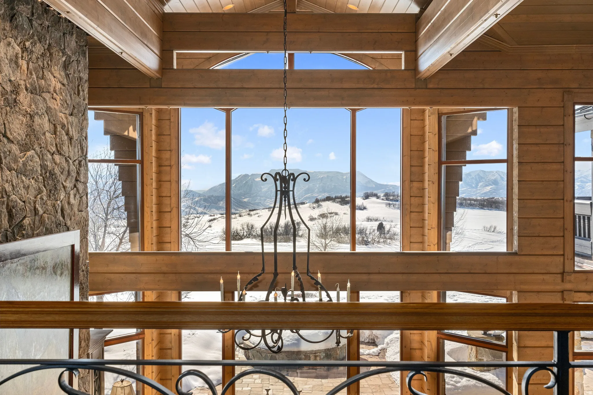 Two-story wall of windows framing a snow-covered mountain landscape