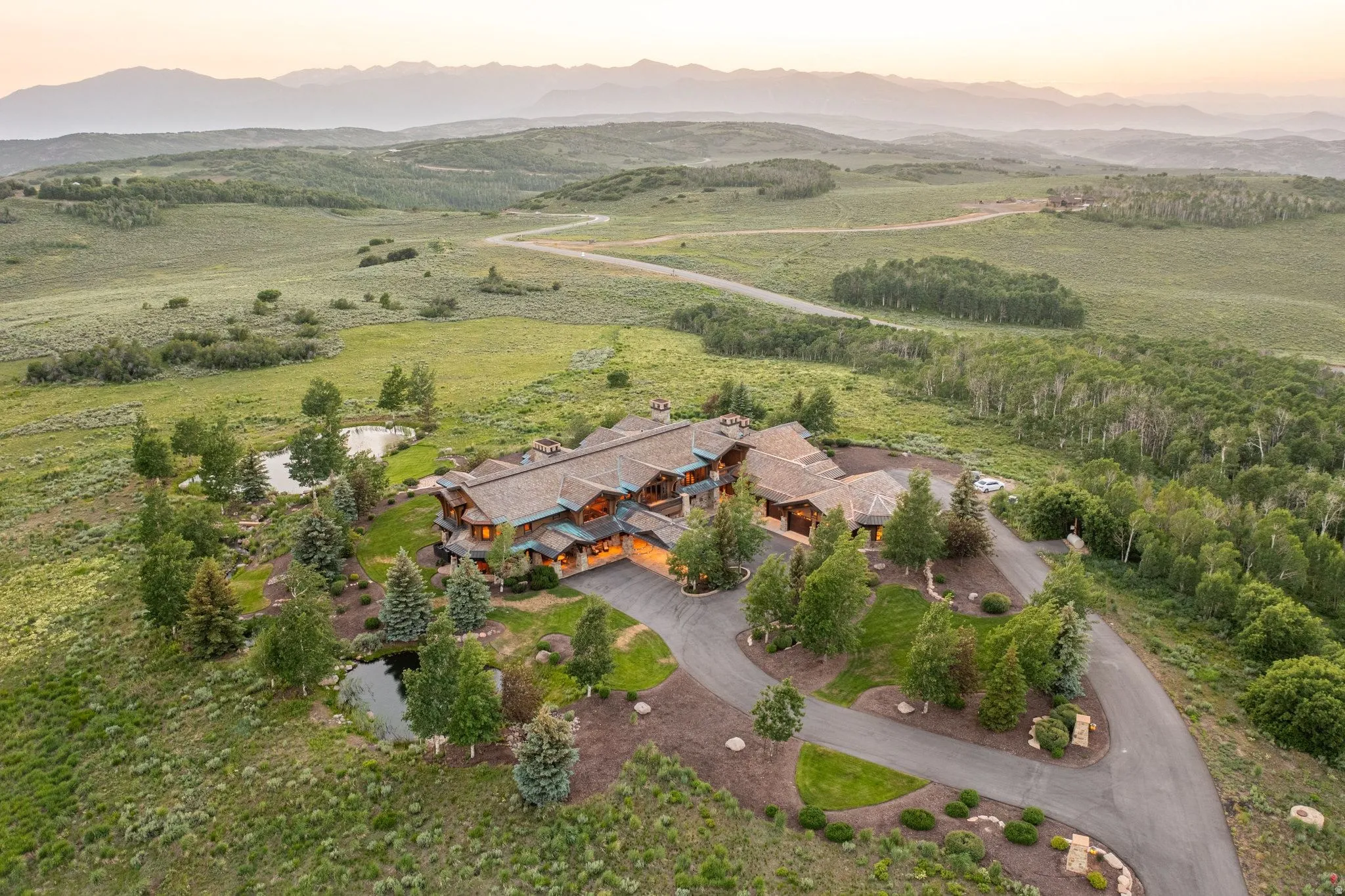 Expansive property featuring a multi-level residence with a distinct roofline, multiple ponds, and mature tree landscaping