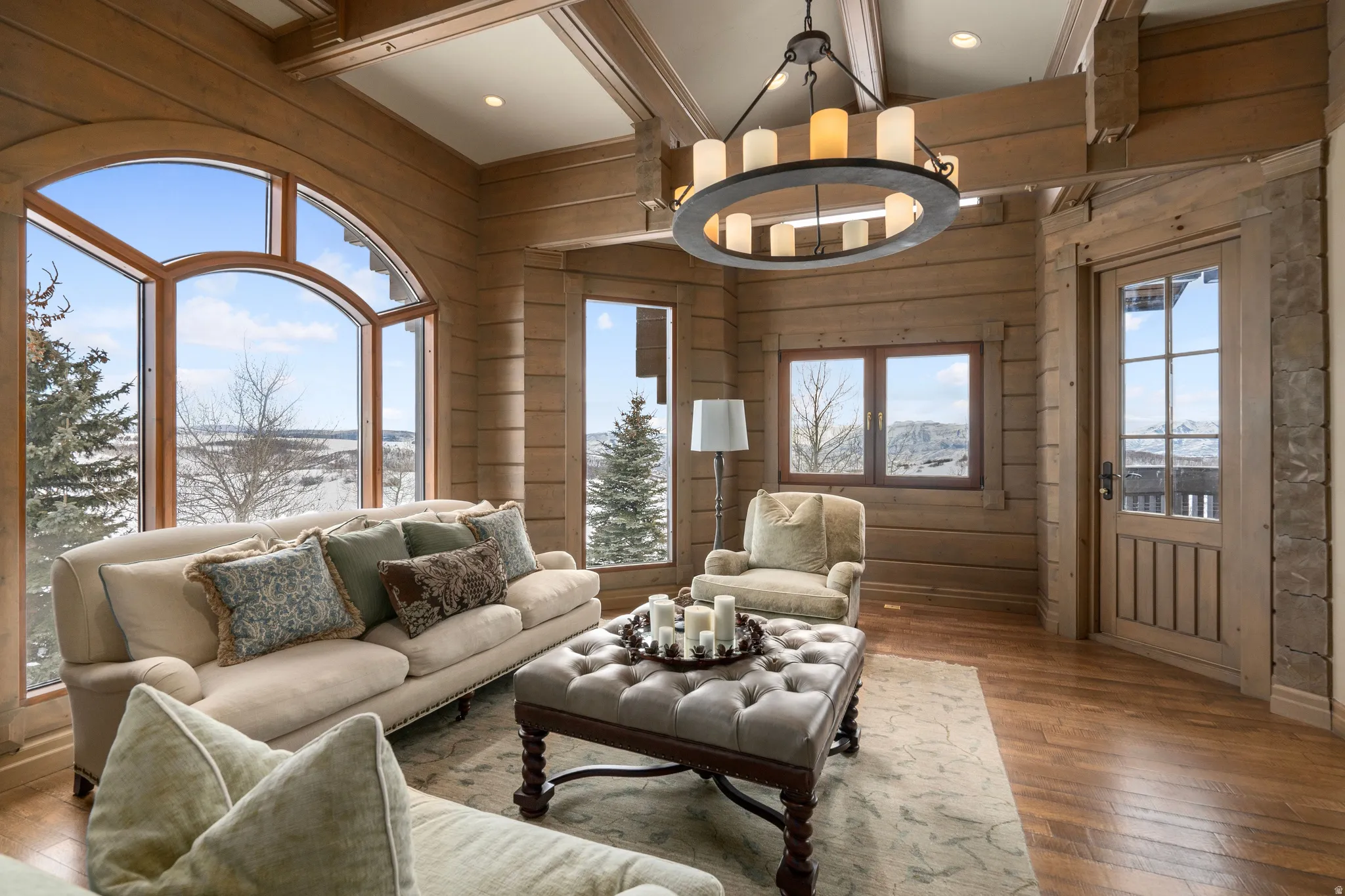 Spacious room featuring extensive wood-finish wall paneling, hardwood flooring, and a coffered ceiling with exposed beams