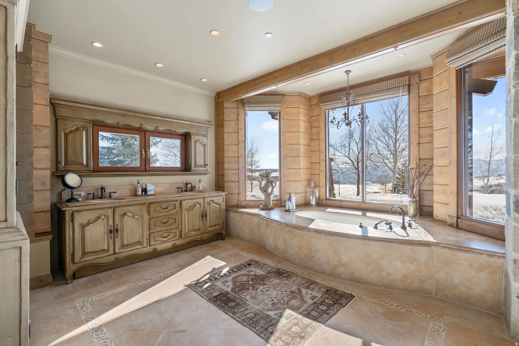Soaking tub with multiple large windows, recessed lighting, and an ornate chandelier