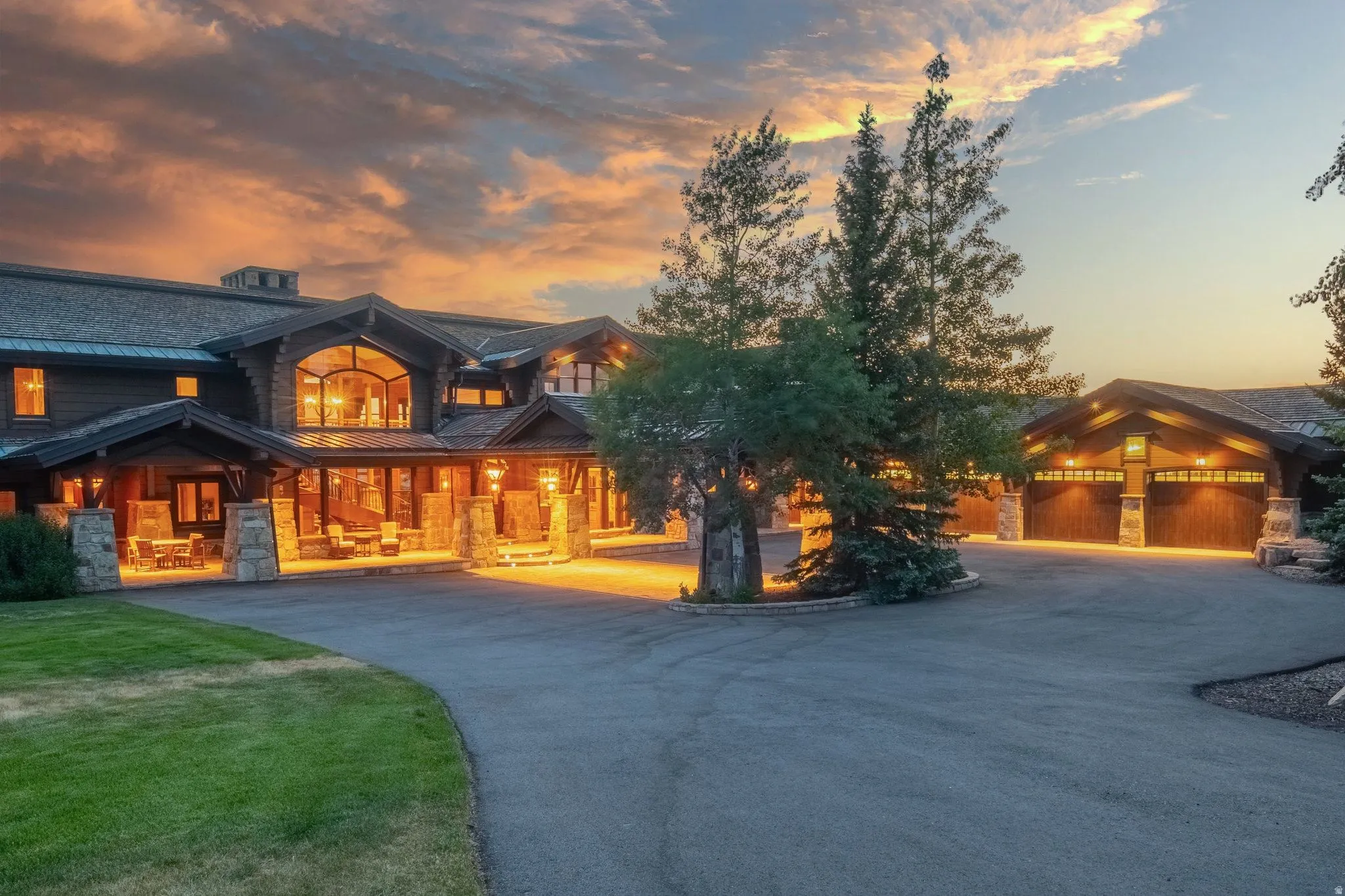 Expansive asphalt driveway leading to a multi-car garage and a grand entryway