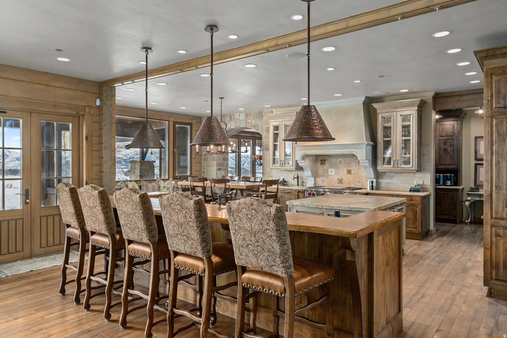 Spacious kitchen featuring a large wood-finish island with seating, pendant lighting, stone countertops, and wood-finish flooring