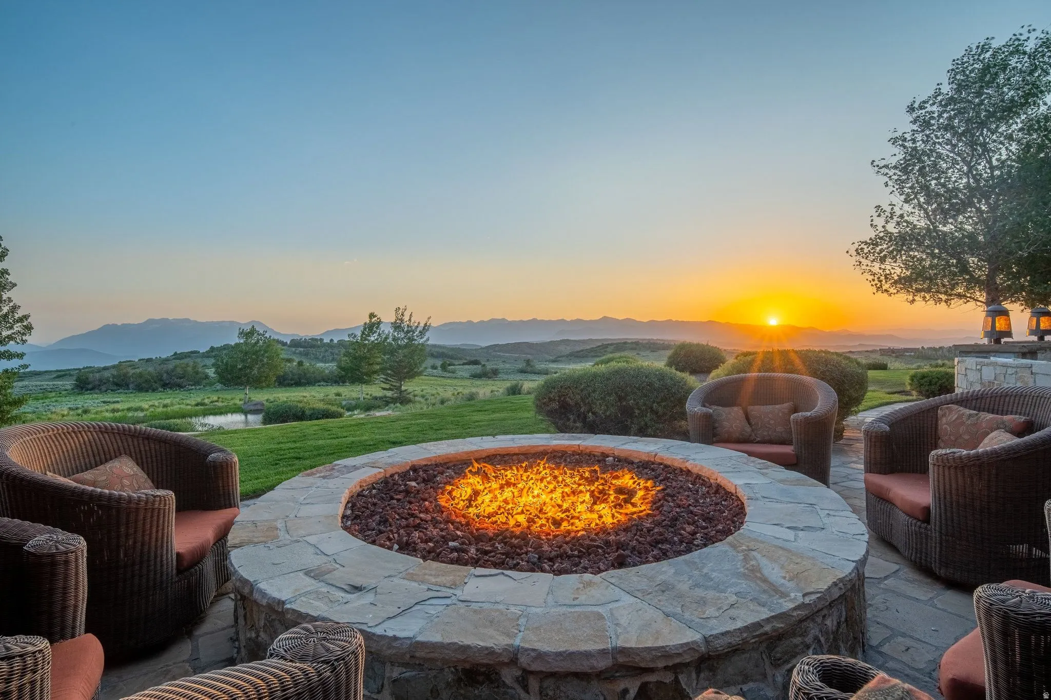 Expansive stone patio featuring a built-in fire pit, surrounded by wicker-style seating