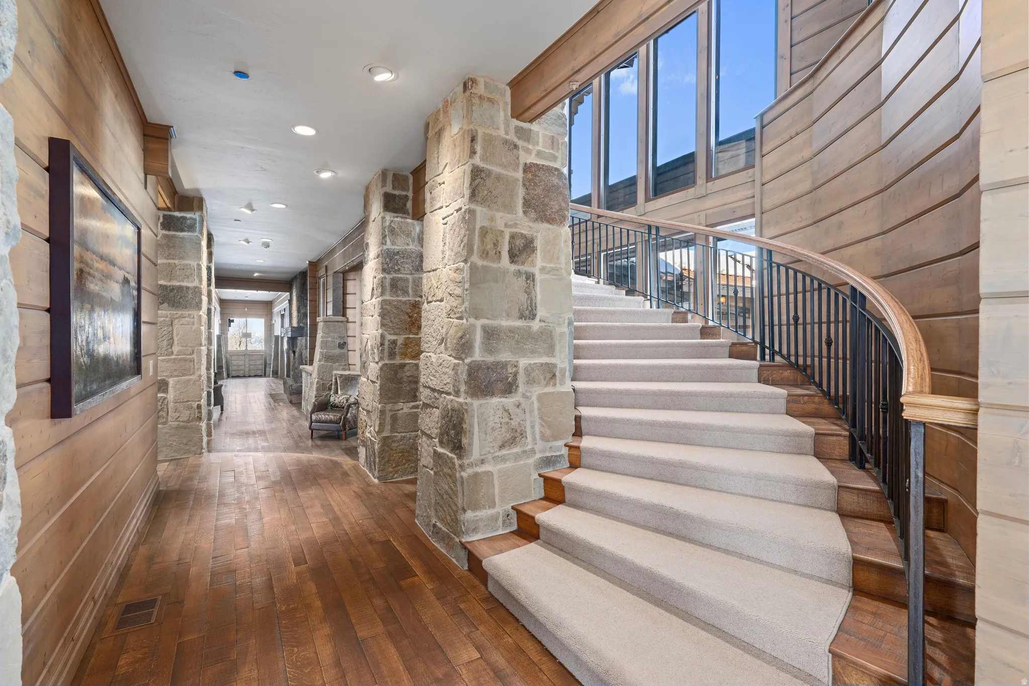 Curved staircase with carpeted treads and an ornate metal railing